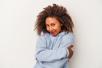 Young african american woman with curly hair isolated on white background hugs, smiling carefree...
