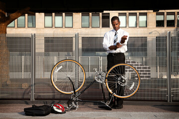 Young businessman rolling sleeves to fix bicycle