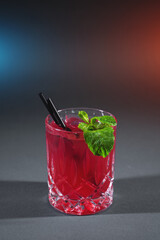 closeup of red strawberry cocktail drink with mint in glass on grey background