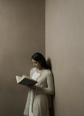 Woman reading book in corner of room