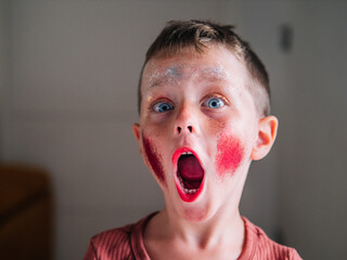 Shocked boy with makeup on face at home