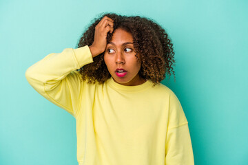 Young african american woman with curly hair isolated on blue background being shocked, she has remembered important meeting.