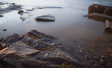 Beautiful ssurface on the shore of the White Sea  with stones and seaweed at sunny morning Belomorsk, Karelia. Long exposure