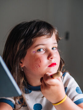 Girl applying glitter on face at home