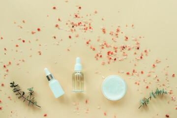 Cosmetic serum, essential oil, cream jar and himalayan salt on beige background. Natural cosmetics and aromatherapy concept. Top view, flat lay