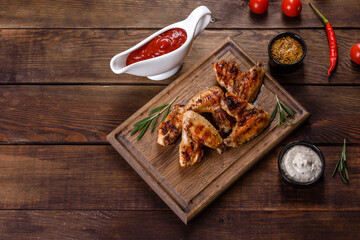 Grilled spicy chicken wings on a dark background with spices and herbs
