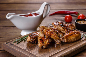 Grilled spicy chicken wings on a dark background with spices and herbs