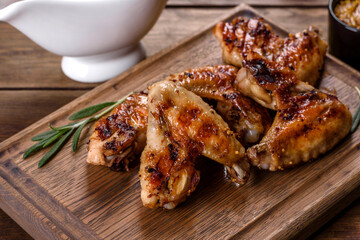 Grilled spicy chicken wings on a dark background with spices and herbs