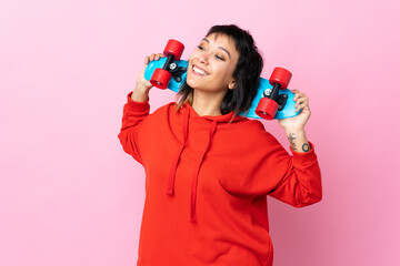 Young Uruguayan woman over isolated pink background with a skate with happy expression