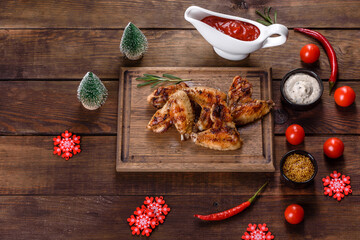 Grilled spicy chicken wings on a dark background with spices and herbs