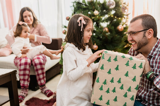 Smiling father passing gift box to daughter on Christmas Day