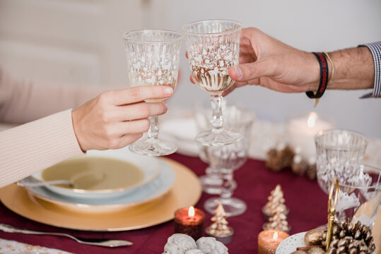 Crop couple clinking glasses of champagne during New Year holiday