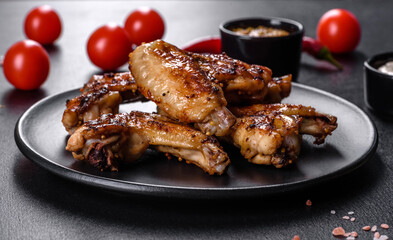 Grilled spicy chicken wings on a dark background with spices and herbs