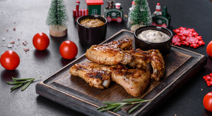 Grilled spicy chicken wings on a dark background with spices and herbs