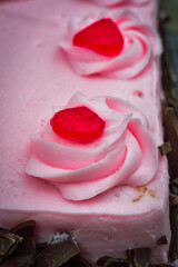 close up detail of piped swirled dollop of pink frosting on top of cake 