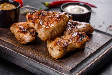 Grilled spicy chicken wings on a dark background with spices and herbs