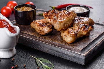 Grilled spicy chicken wings on a dark background with spices and herbs