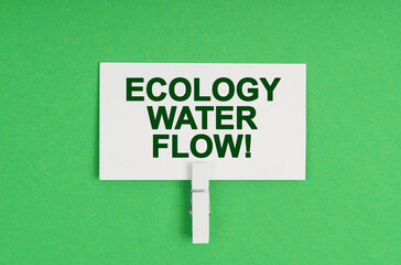 On a green background, a business card on a clothespin. The business card says - Ecology Water Flow