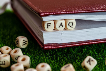 wooden cubes are clamped in a notebook, the word FAQ, the idea of solving questions
