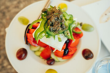 Greek salad. Traditional vegetable dish with cucumbers, tomatoes, green bell pepper, red onion, olives and feta cheese. Vegetarian food.