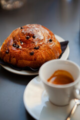 The table with sweets (pastries: croissant, cookies), white cups (mug) with hot black coffee (espresso), the saucer, the spoons at a local bar. Traditional Italian breakfast. Milan, Lombardy, Italy