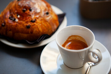 The table with sweets (pastries: croissant, cookies), white cups (mug) with hot black coffee (espresso), the saucer, the spoons at a local bar. Traditional Italian breakfast. Milan, Lombardy, Italy