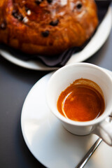 The table with sweets (pastries: croissant, cookies), white cups (mug) with hot black coffee (espresso), the saucer, the spoons at a local bar. Traditional Italian breakfast. Milan, Lombardy, Italy