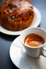 The table with sweets (pastries: croissant, cookies), white cups (mug) with hot black coffee (espresso), the saucer, the spoons at a local bar. Traditional Italian breakfast. Milan, Lombardy, Italy