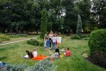 A teacher teaches a class of children in an outdoor Park. Back to school, learning during the...