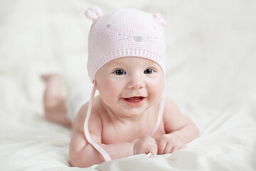 Newborn baby girl in pink knitted hat on a bed. 