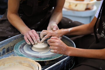 Master of ceramics teaches a student. the student sculpted a pottery. The master sculpts clay with his hands. Learning in the form of a game.