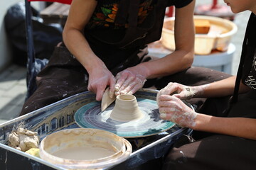 Master of ceramics teaches a student. the student sculpted a pottery. The master sculpts clay with his hands. Learning in the form of a game.
