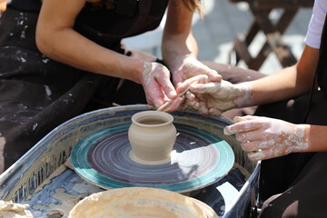 Master of ceramics teaches a student. the student sculpted a pottery. The master sculpts clay with his hands. Learning in the form of a game.