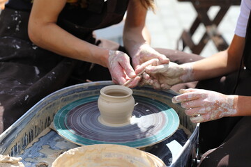 Master of ceramics teaches a student. the student sculpted a pottery. The master sculpts clay with his hands. Learning in the form of a game.