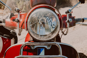 Fototapeta premium Headlight of red retro scooter. Design details of brand-new motor bike close-up.