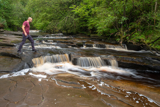 Man crossing falls at Glenbarrow river. Co. Laois, Ireland
