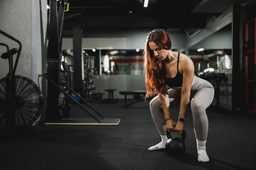 Fototapeta na wymiar Muscular Woman Doing Training With Kettlebell At The Gym