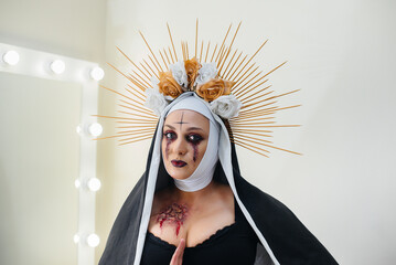 A young girl in a beautiful festive makeup and a scary nun costume for the Halloween holiday. Happy...