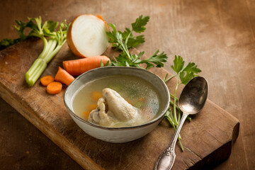 chicken soup witn ingredients over cutting board