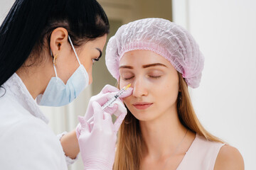 Cosmetic procedure for filling the nasolacrimal furrow and mesotherapy around the eyes for a young...