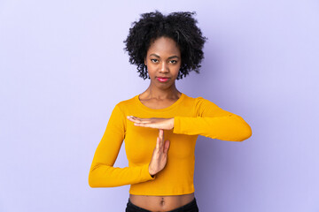 Young African American woman isolated on purple background making time out gesture