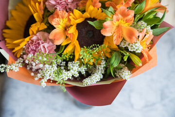 Fresh Bouquet of yellow sunflowers and pink carnations on marble background. flower shop. A variant of a bouquet on an autumn theme, for Thanksgiving.