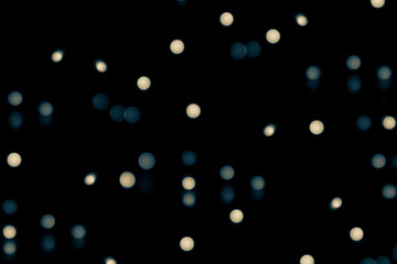 Blurred, defocused background with bokeh effect. Blue and yellow light circles on a black background