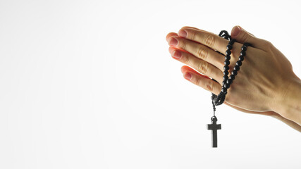 Rosary and crucifix in female hands on a white background. Hands folded for prayer. Religion,...
