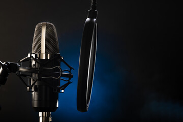 Professional microphone and pop filter. Dark blue background. Minimalism. No people. Recording...