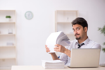 Young male employee unhappy with excessive work in the office