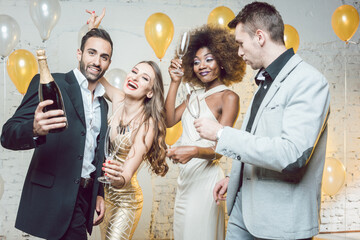 Group of women and men celebrating new years eve or a birthday with champagne - obrazy, fototapety, plakaty