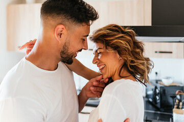 Lovely couple hugging and smiling while having fun together in the kitchen at home. Relationship concept.