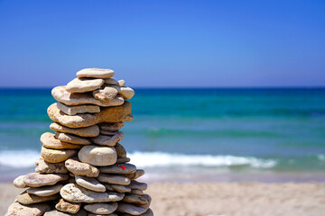 Fototapeta na wymiar Big waves on the beach, the ocean. A pyramid of stones, pebbles, a slide built by a child on the beach