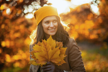 smiling stylish woman in beige coat and hat